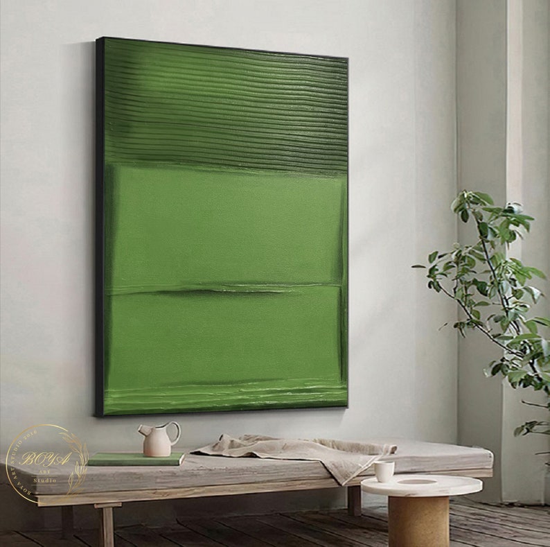 Puede incluir: Pintura abstracta con rayas horizontales verdes y una superficie texturizada. La pintura est&aacute; enmarcada en negro y cuelga de una pared blanca.
