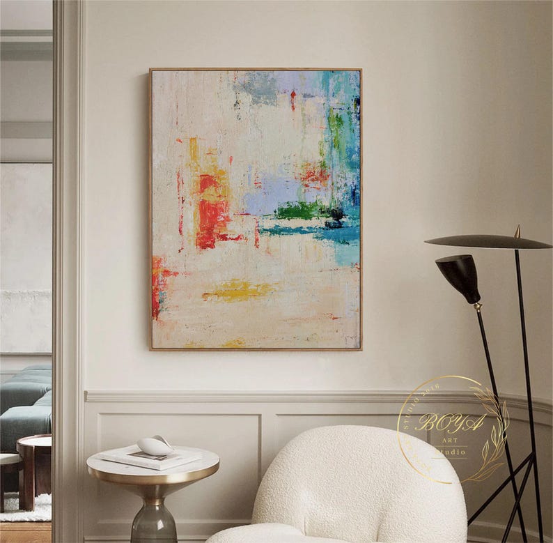 Peut inclure: Peinture abstraite sur fond blanc avec des coups de pinceau color&eacute;s dans des tons de bleu, vert, jaune et rouge. La peinture est encadr&eacute;e d'un cadre fin et dor&eacute;.