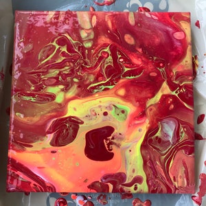 May include: Square abstract art piece with a vibrant mix of red, yellow, and green hues. The fluid design features swirling patterns and color gradients, creating a dynamic and eye-catching visual effect. The artwork is on a square canvas.