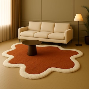 May include: A contemporary living room with a rust-coloured, cloud-shaped rug with a cream border. A beige sofa, dark brown coffee table, and a floor lamp are present. The room has a neutral colour palette, creating a warm and inviting atmosphere.