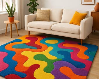 May include: A vibrant, colorful area rug with an abstract design. The rug features a mix of bright colors including red, orange, yellow, green, blue, and purple. The rug is placed in a living room setting with a cream-colored sofa.