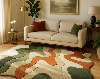 Puede incluir: Una alfombra moderna con un diseño abstracto en tonos verdes, naranjas y crema. La alfombra está colocada sobre un suelo de madera en un salón, con un sofá beige y cojines decorativos.