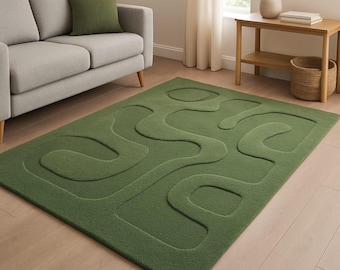 May include: A green rectangular rug with a raised, abstract design. The rug is a solid shade of green and features a textured pattern of curved lines. The rug is placed on a light-colored wooden floor, and a gray sofa and green pillow are in the background.