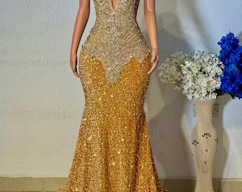Puede incluir: Un vestido de lentejuelas dorado de estilo sirena con escote pronunciado y un corpiño de encaje transparente. El vestido está adornado con lentejuelas y cuentas brillantes.