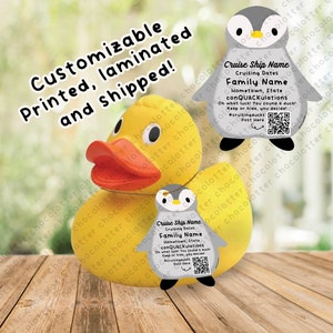 May include: A yellow rubber duck with a gray penguin tag attached. The tag has the text "Cruise Ship Name", "Cruising Dates", "Family Name", "Hometown, State", "conQUACKulations", "Oh what luck! You found a duck! Keep or hide, you decide! #cruisingducks", and a QR code. The duck is sitting on a wooden surface.
