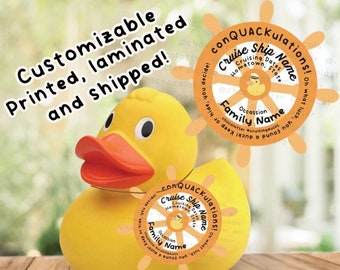 May include: A yellow rubber duck with a red beak and orange feet. The duck is wearing a white and orange life preserver with the text "conQUACKulations!" and "Cruise Ship Name" on it. The life preserver also has a small yellow rubber duck with a red beak and orange feet on it.