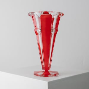 May include: A red and clear glass vase with a geometric design. The vase has a wide mouth and a narrow base.