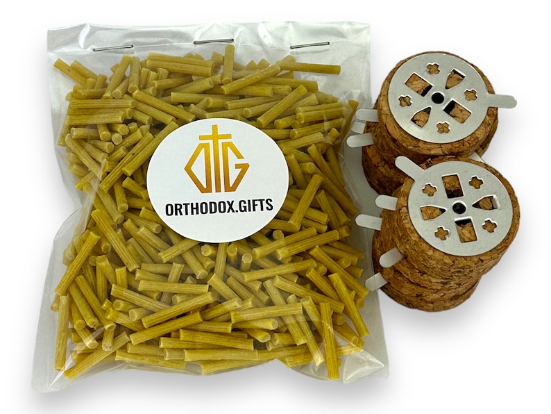May include: A clear plastic bag filled with yellow beeswax sticks. Next to the bag are three round cork incense holders with metal tops featuring a cross design. The bag has a white label with the text "ORTHODOX.GIFTS" and a cross symbol.