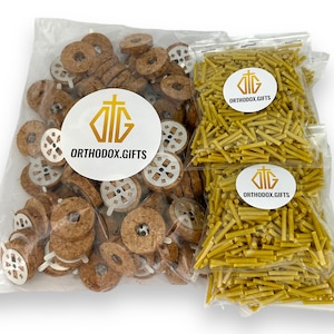 May include: Two clear plastic bags filled with craft supplies. One bag contains a large quantity of small, round, brown cork candle holders with a metal cross design. The other bag contains a large quantity of thin, yellow wax candle sticks. Both bags have a white label with the text "ORTHODOX.GIFTS" and a gold cross.