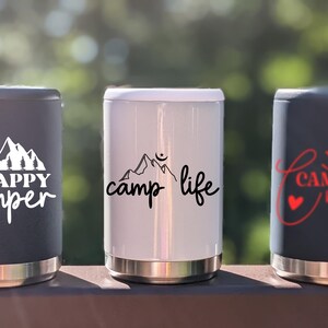Puede incluir: Tres contenedores de bebidas aislados con diferentes dise&ntilde;os. El primer contenedor es negro con texto blanco que dice "HAPPY Camper" y un gr&aacute;fico de cordillera. El segundo contenedor es blanco con texto negro que dice "camp life" y un gr&aacute;fico de cordillera. El tercer contenedor es negro con texto rojo que dice "CAMPING crew" y un gr&aacute;fico de coraz&oacute;n.