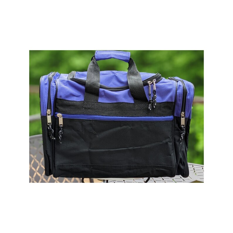 K&ouml;nnte beinhalten: Eine blaue und schwarze Reisetasche mit zwei Rei&szlig;verschlussf&auml;chern und einem Tragegriff.