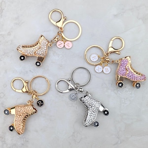 May include: Roller skate keychains in gold, silver, and rose gold tones, each adorned with sparkling rhinestones. The keychains feature black wheels and are accented with charms bearing letters. A fun accessory.