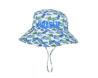 May include: White bucket hat with a blue dinosaur print and the name "Charlie" in blue lettering.