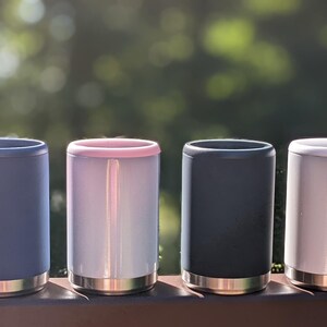 Puede incluir: Siete enfriadores de latas aislados en varios colores, incluyendo rosa, azul, blanco y negro. Los enfriadores est&aacute;n hechos de acero inoxidable y tienen un dise&ntilde;o de doble pared para mantener las bebidas fr&iacute;as.