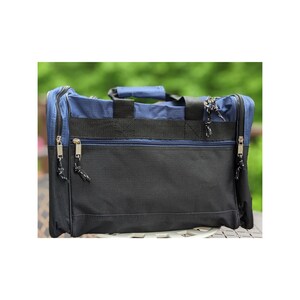 K&ouml;nnte beinhalten: Eine blaue und schwarze Reisetasche mit zwei Rei&szlig;verschlussf&auml;chern und einem Tragegriff.