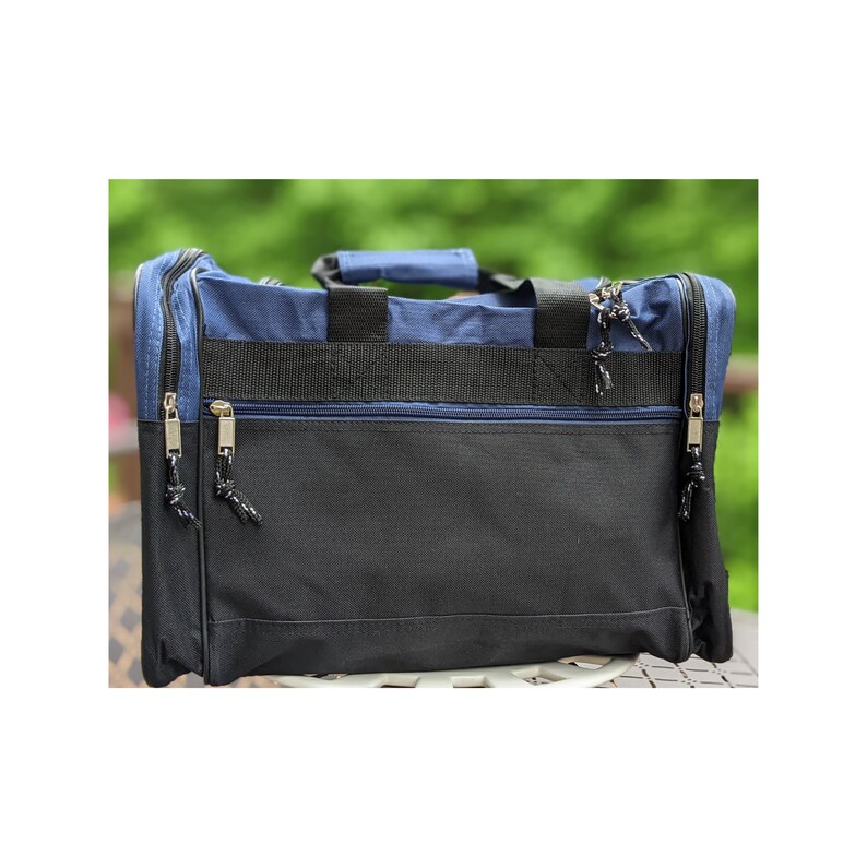 K&ouml;nnte beinhalten: Eine blaue und schwarze Reisetasche mit zwei Rei&szlig;verschlussf&auml;chern und einem Tragegriff.