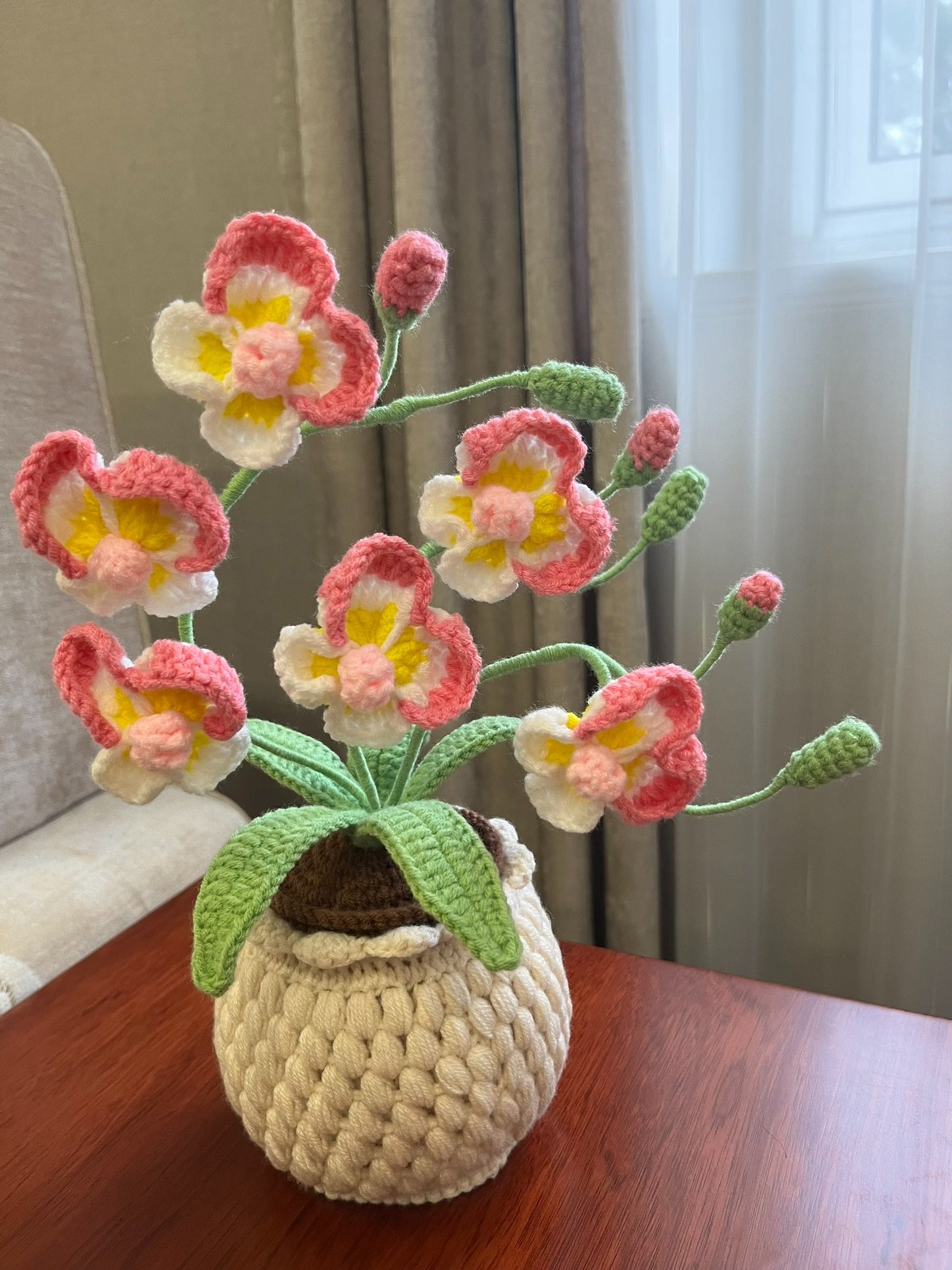 完成したかぎ針編みの胡蝶蘭の鉢植え、葉とつぼみのある編み物の胡蝶蘭