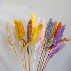 May include: A bouquet of faux pampas grass stems in various colors, including white, yellow, pink, purple, and brown. The stems are made of fluffy, textured material and are perfect for adding a touch of natural beauty to any space.