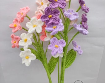 May include: A bouquet of crocheted flowers in shades of pink, white, and purple. The flowers are arranged in a vase and have green stems and leaves. The text "Endless Love" is written on the background.