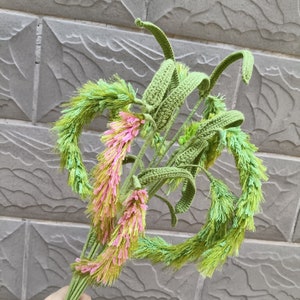 May include: A bouquet of crocheted flowers with green stems and pink and green petals.
