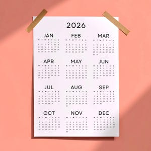 May include: A white 2026 calendar with a monthly layout, taped to a pink background. Each month is displayed with its days and dates in a simple, easy-to-read format. The calendar is held in place with two pieces of tan tape.