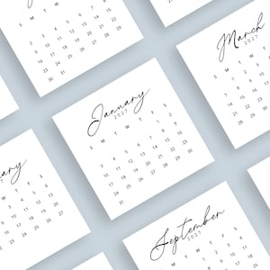 May include: A collection of white square calendars for the year 2027, each displaying a different month. The months are written in an elegant script font. The calendars are arranged on a light blue surface.