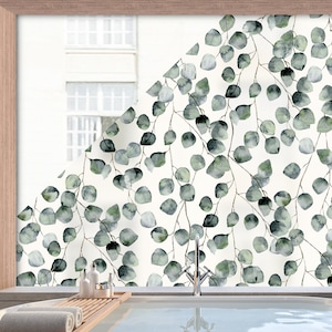 Könnte beinhalten: Eine Fensterfolie mit einem Aquarellmuster aus grünen Eukalyptusblättern auf weißem Hintergrund. Die Folie ist an einem Fenster in einem Badezimmer angebracht.
