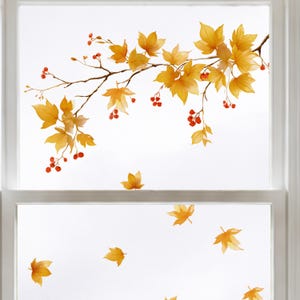 Könnte beinhalten: Ein Fensteraufkleber mit einem horizontalen Zweig, goldenen Herbstblättern und kleinen roten Beeren. Mehrere einzelne gelbe Blätter sind unterhalb des Zweigs verteilt und bilden eine herbstliche Dekoration auf der Glasfläche.