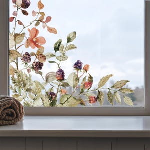 Könnte beinhalten: Ein Fensteraufkleber mit einer Aquarellillustration von Brombeerzweigen mit grünen Blättern, orangefarbenen Blüten und dunkelvioletten Beeren. Das botanische Design ist auf der Glasscheibe angebracht und zeigt detaillierte Texturen und Farben.