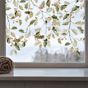 May include: A window film featuring a repeating pattern of oak branches with green and tan leaves and small brown acorns. The design is semi-transparent, allowing light to pass through while displaying the detailed botanical illustration.
