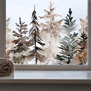 Peut inclure: Un autocollant pour fenêtre représentant une forêt à l'aquarelle avec divers conifères dans des tons de brun, de gris et de vert sourd. Le motif dépeint un paysage boisé dense avec des pins superposés, créant un effet semi-transparent sur le verre.