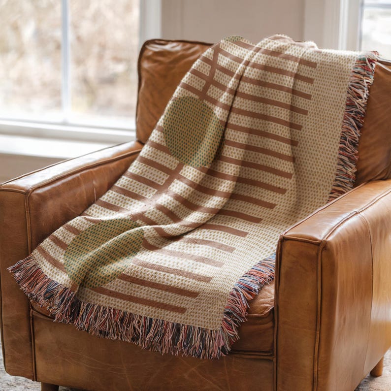 A brown leather armchair with a colorful woven blanket draped over it, placed near a window.
