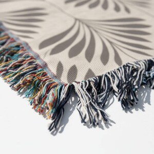 A close-up view of a decorative fabric with a leaf-like pattern, featuring a mix of multicolored fringe and a textured background.