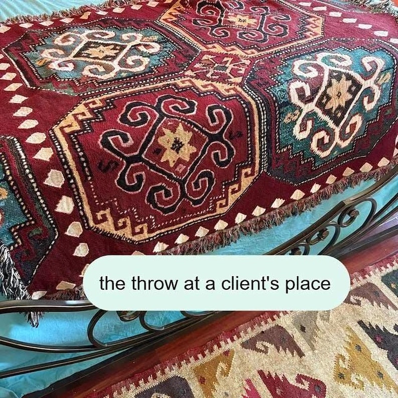 a colorful, intricately patterned rug or carpet placed on a metal frame, with a caption that reads "the throw at a client's place".