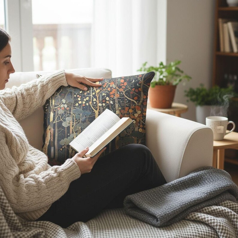 A person is sitting on a couch, reading a book and holding a cup of coffee.
