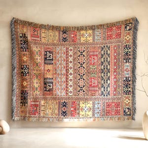 May include: A rectangular woven throw blanket featuring a multi-colored pattern of vertical and horizontal geometric stripes, intricate tribal-inspired motifs, and a fringed border in shades of red, blue, yellow, and cream on a textured fabric.