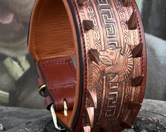 May include: A brown leather dog collar with a copper-colored decorative design. The collar features a series of copper spikes and an embossed pattern with a mythical creature. The collar has a brass buckle.