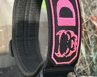 May include: Black dog collar with a pink embroidered patch that says "DIK" and has a dog silhouette. The collar has a metal D-ring and a buckle.