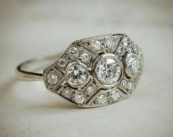 May include: A silver ring with a large, round, center diamond surrounded by smaller diamonds in a geometric pattern.