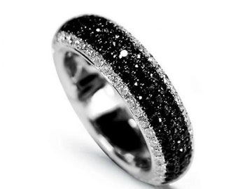 May include: A silver ring with a band of black stones and a row of white stones. The ring is set against a white background, highlighting its design and sparkle. This piece is suitable for everyday wear or special occasions.