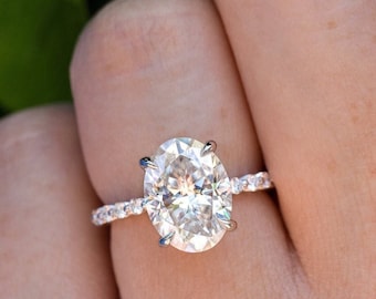 May include: A silver engagement ring with a large oval-shaped diamond and a pave diamond band.