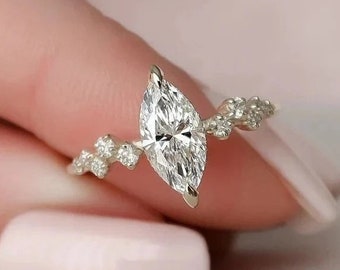 May include: A gold engagement ring with a large marquise-shaped diamond and smaller diamonds set in a delicate band.