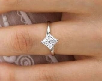 May include: A silver ring with a square-shaped diamond set in the center.