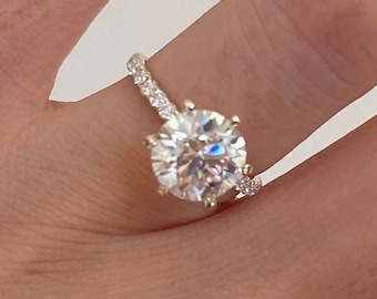 May include: A gold engagement ring with a large, round, clear diamond center stone and a band of smaller diamonds.
