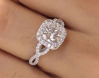 May include: A silver engagement ring with a large, square-cut diamond surrounded by smaller diamonds. The band is a twisted design with smaller diamonds set along the band.