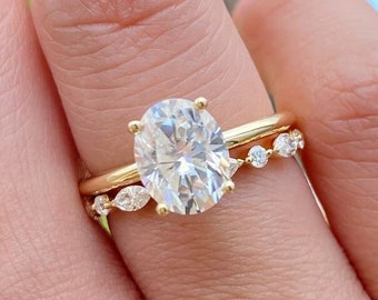 May include: A gold band with a large oval-shaped diamond and a smaller band with smaller diamonds set in a pave setting.