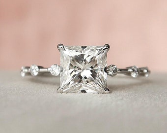 May include: A silver engagement ring with a large, square-cut diamond and a delicate band of smaller diamonds.