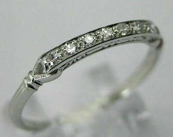 May include: A delicate silver band ring with a row of small, sparkling diamonds set in a curved design.
