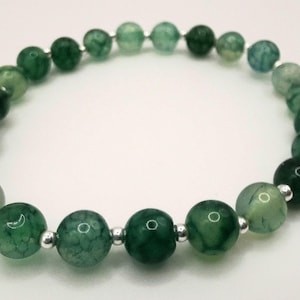 Op de afbeelding: Een armband van groene agaat kralen met zilveren tussenstukken. De kralen zijn rond en hebben een natuurlijke, gemarmerde uitstraling.