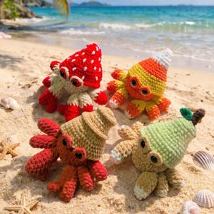 May include: Four colorful crochet octopus toys on a sandy beach. One is red with white spots, another is yellow and orange, a third is brown, and the last is green. The toys have large eyes and are designed to look like various foods.